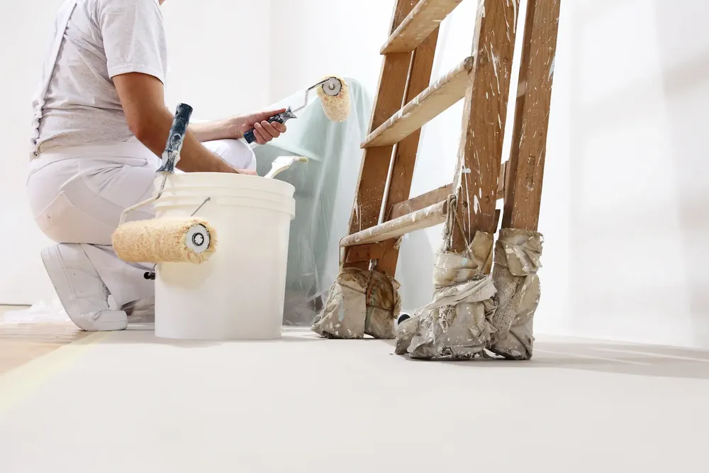Painter working on site, with paint and a ladder visible