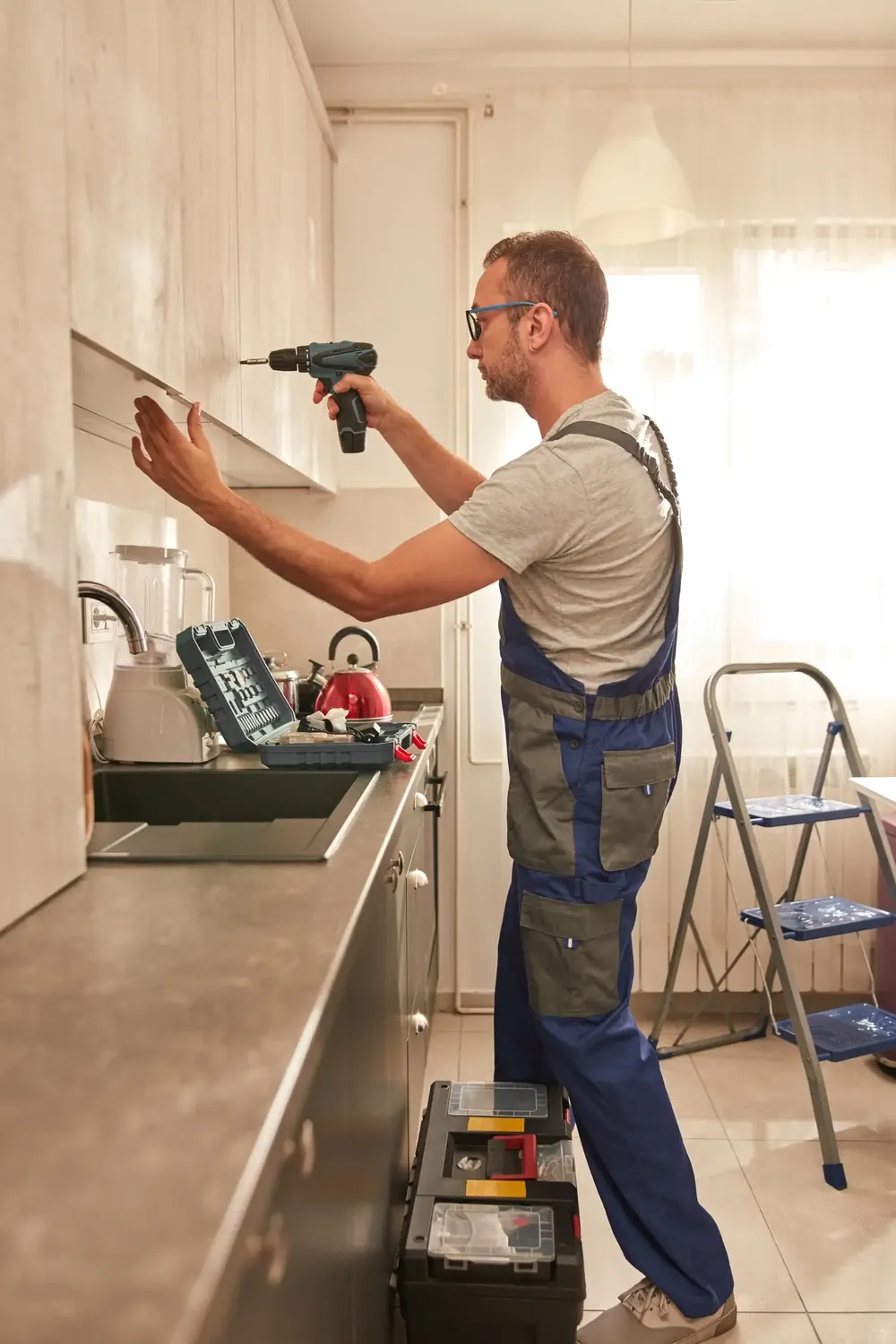 Handyman drilling in a cabinet in a kitchen