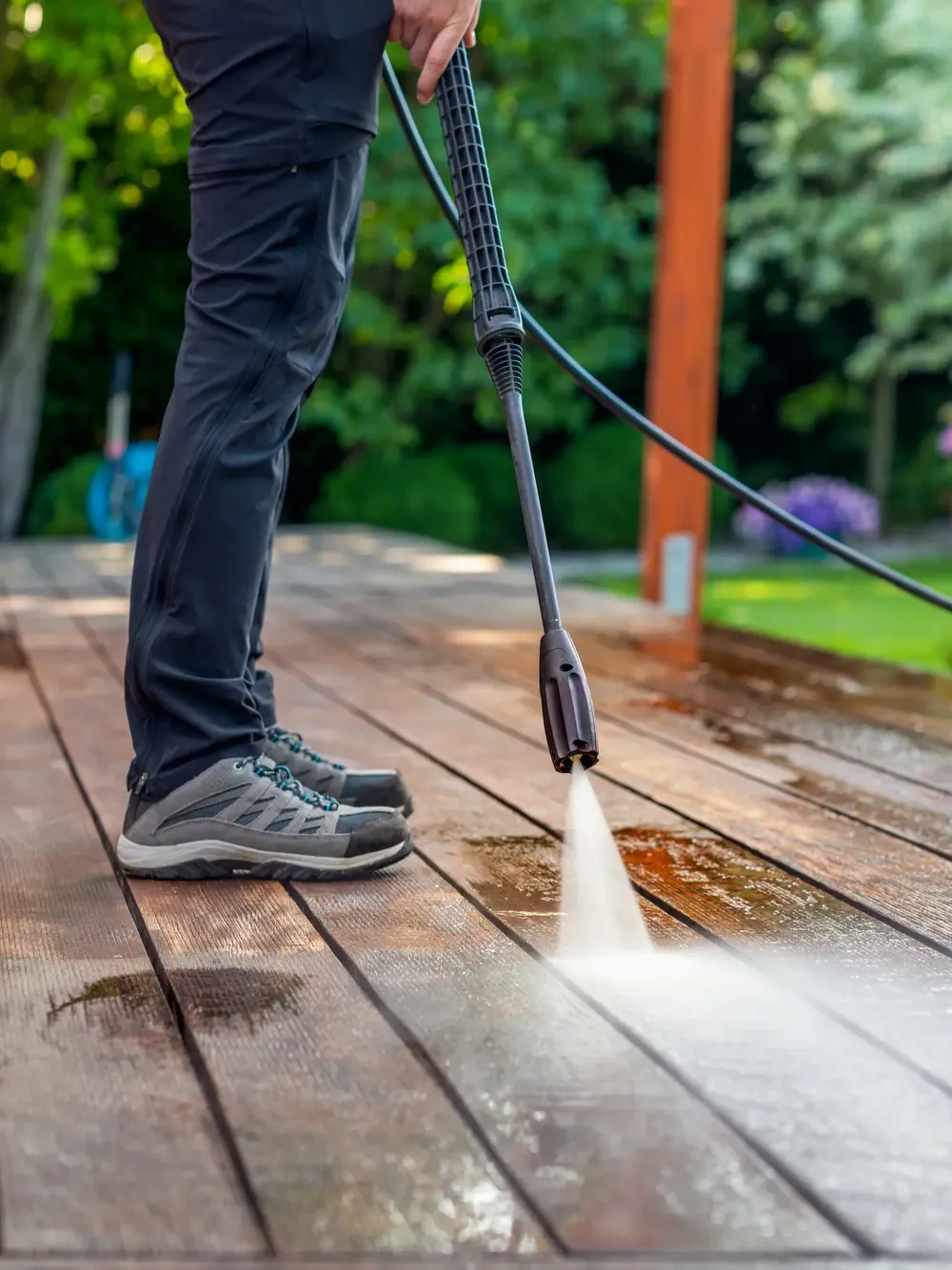 A contractor pressure washing a wooden deck