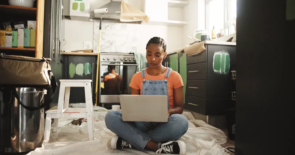 Handyman sitting on the floor viewing a website on their laptop